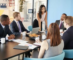 female-manager-stands-addressing-colleagues-in-meeting-room.jpg female-manager-stands-addressing-colleagues-in-meeting-room.jpg